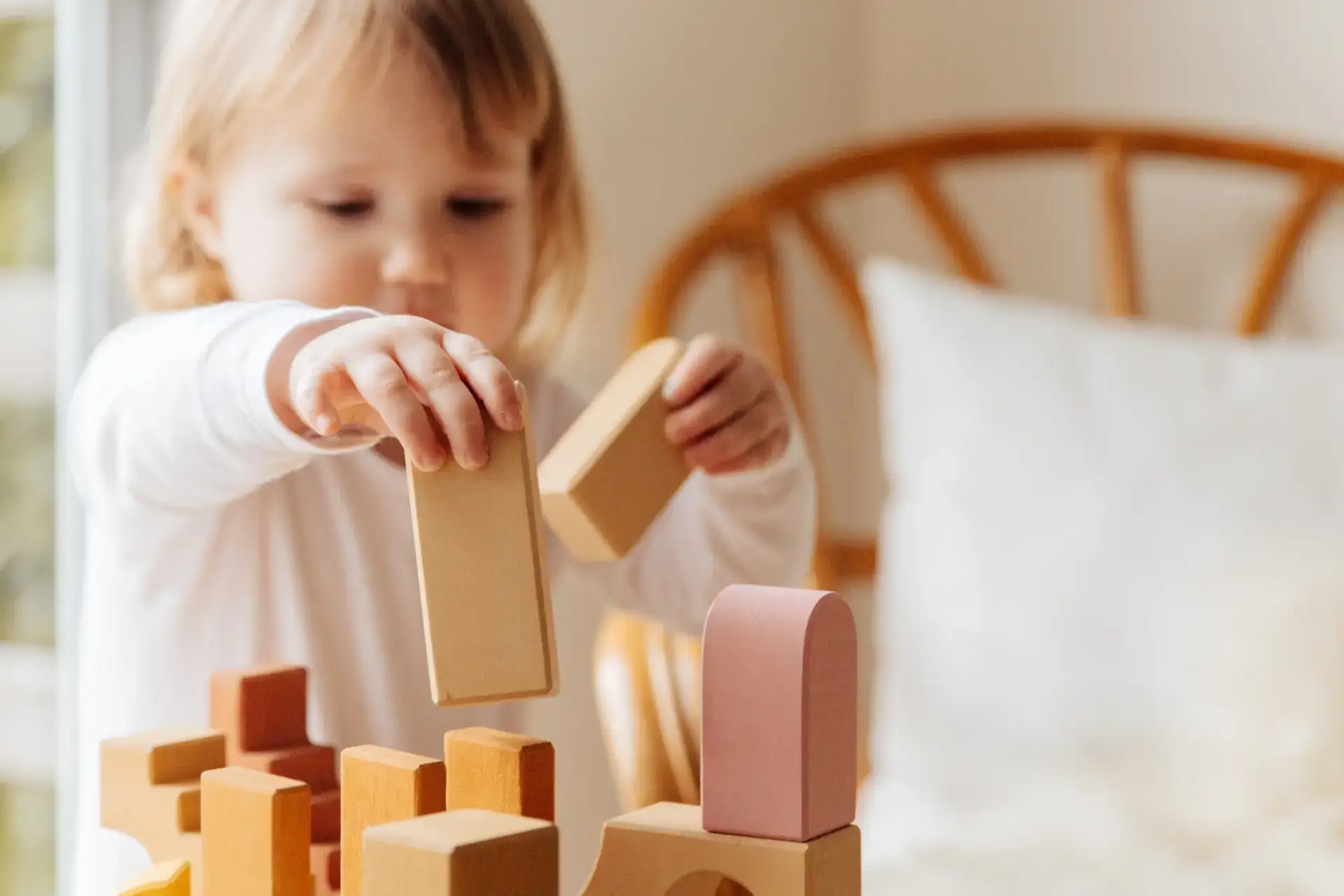 Child arranging wooden building blocks at home.